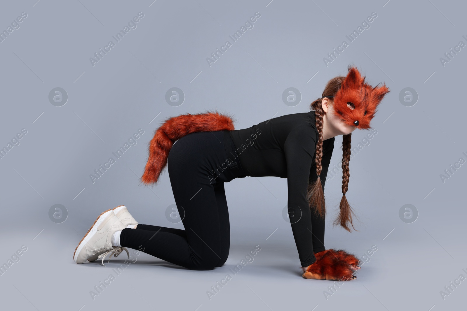 Photo of Quadrobics. Girl wearing fox mask, gloves and tail on grey background