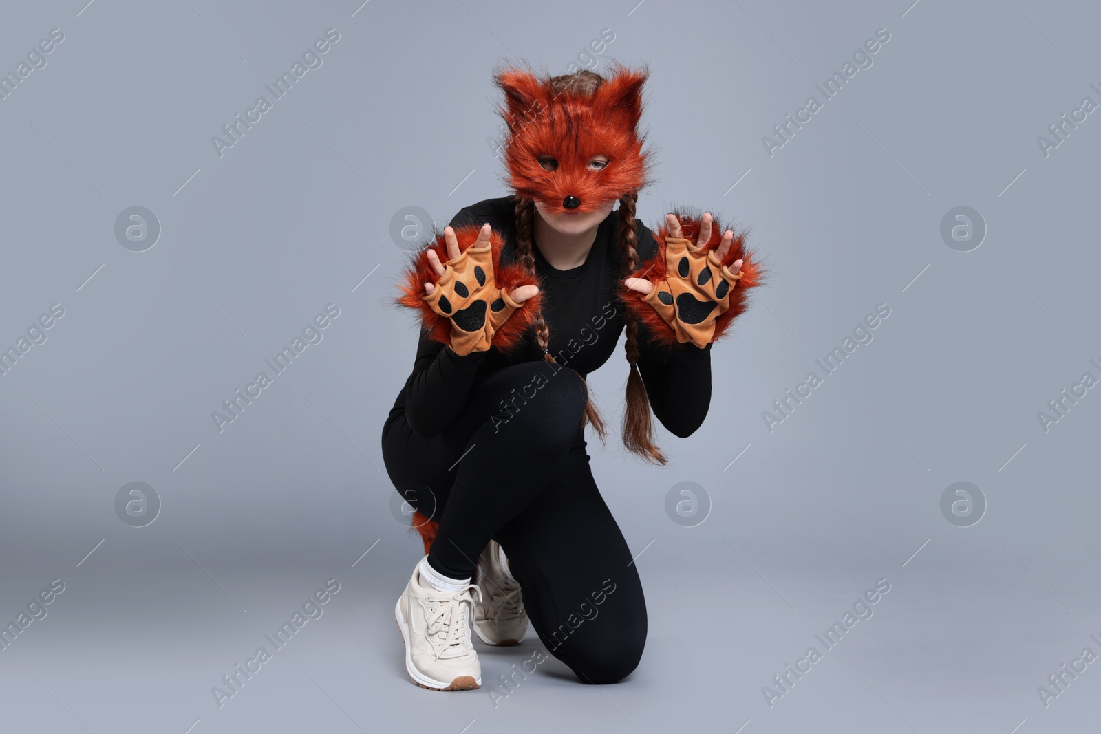 Photo of Quadrobics. Girl wearing fox mask and gloves on grey background