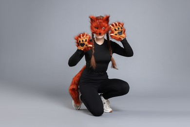 Photo of Quadrobics. Girl wearing fox mask, gloves and tail on grey background