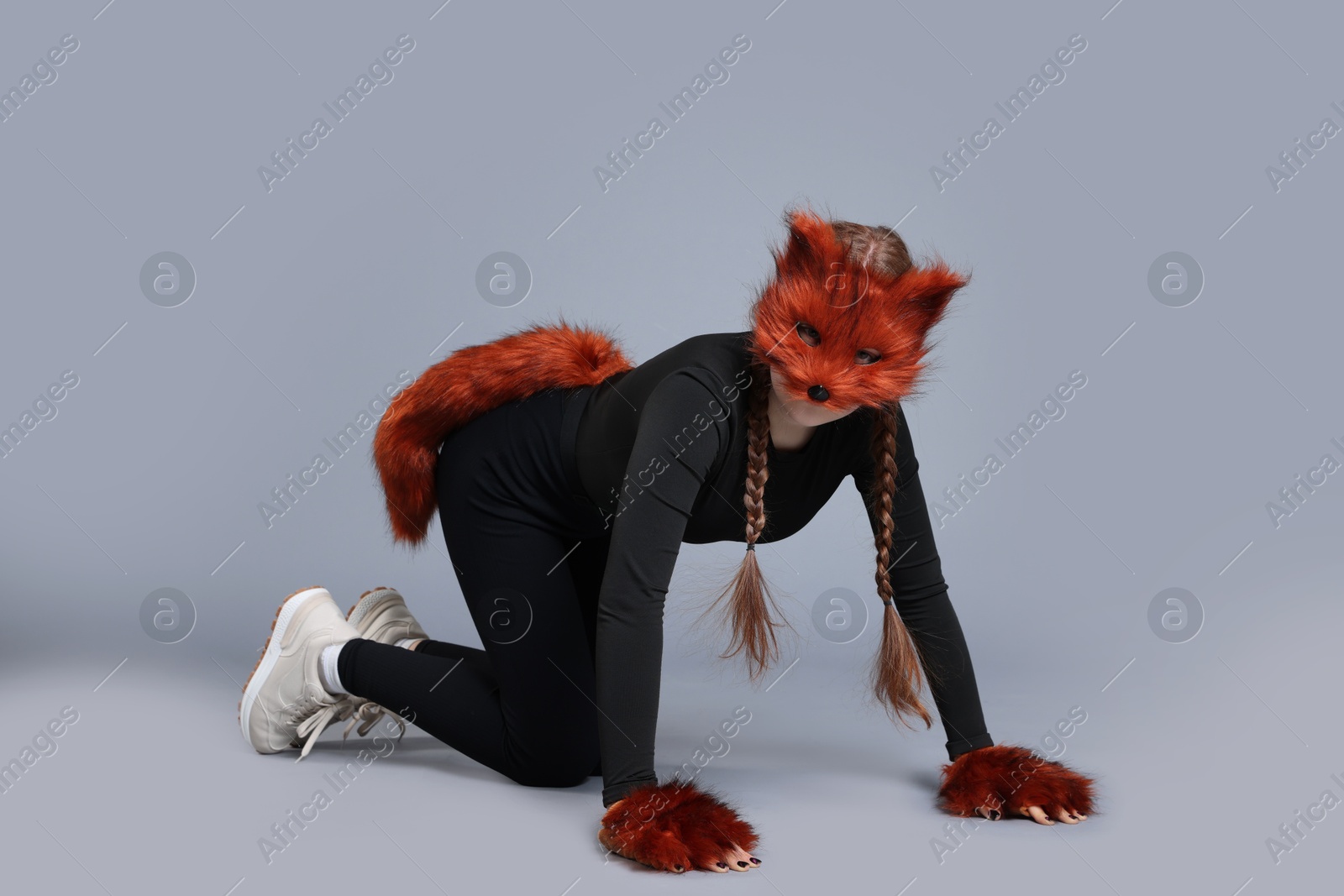 Photo of Quadrobics. Girl wearing fox mask, gloves and tail on grey background