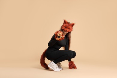 Photo of Quadrobics. Girl wearing fox mask, gloves and tail on beige background