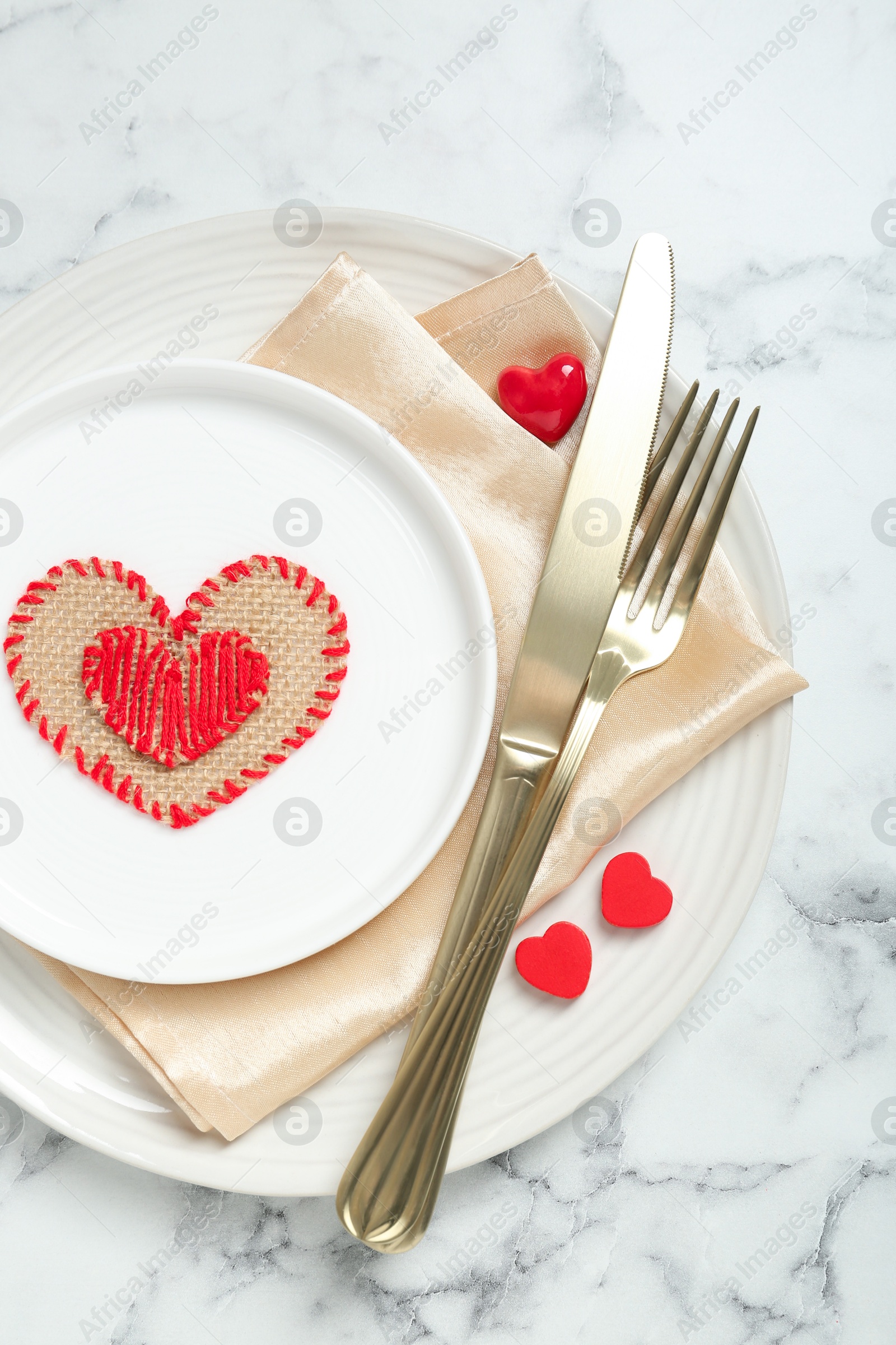 Photo of Romantic place setting for Valentine's day. Tableware, cutlery and decorative hearts on white marble table, top view