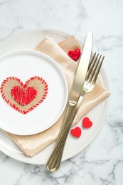 Photo of Romantic place setting for Valentine's day. Tableware, cutlery and decorative hearts on white marble table, top view