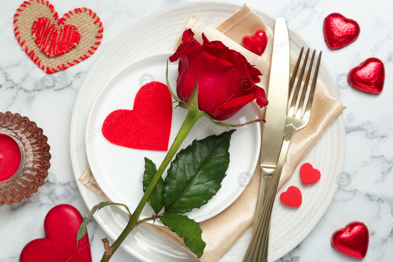 Photo of Romantic place setting for Valentine's day. Tableware, cutlery, rose and decorative hearts on white marble table, flat lay