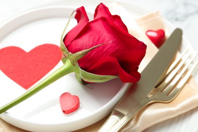 Photo of Romantic place setting for Valentine's day. Rose, tableware, cutlery and decorative hearts on white table, closeup