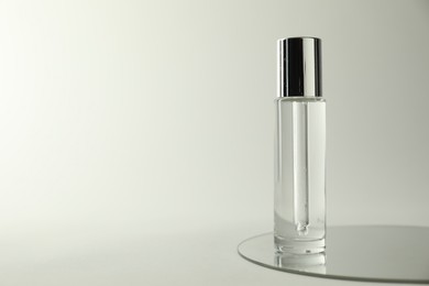 Photo of Bottle of serum and mirror on light background, space for text