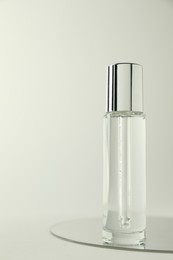 Photo of Bottle of serum and mirror on light background, space for text