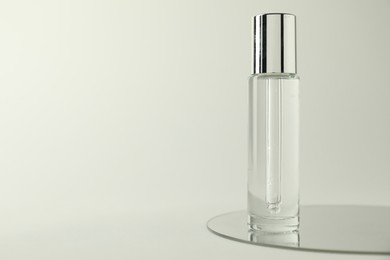 Photo of Bottle of serum and mirror on light background, space for text