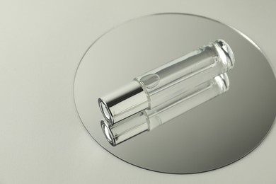 Photo of Bottle of serum and mirror on light background, space for text