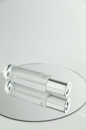 Photo of Bottle of serum and mirror on light background, space for text