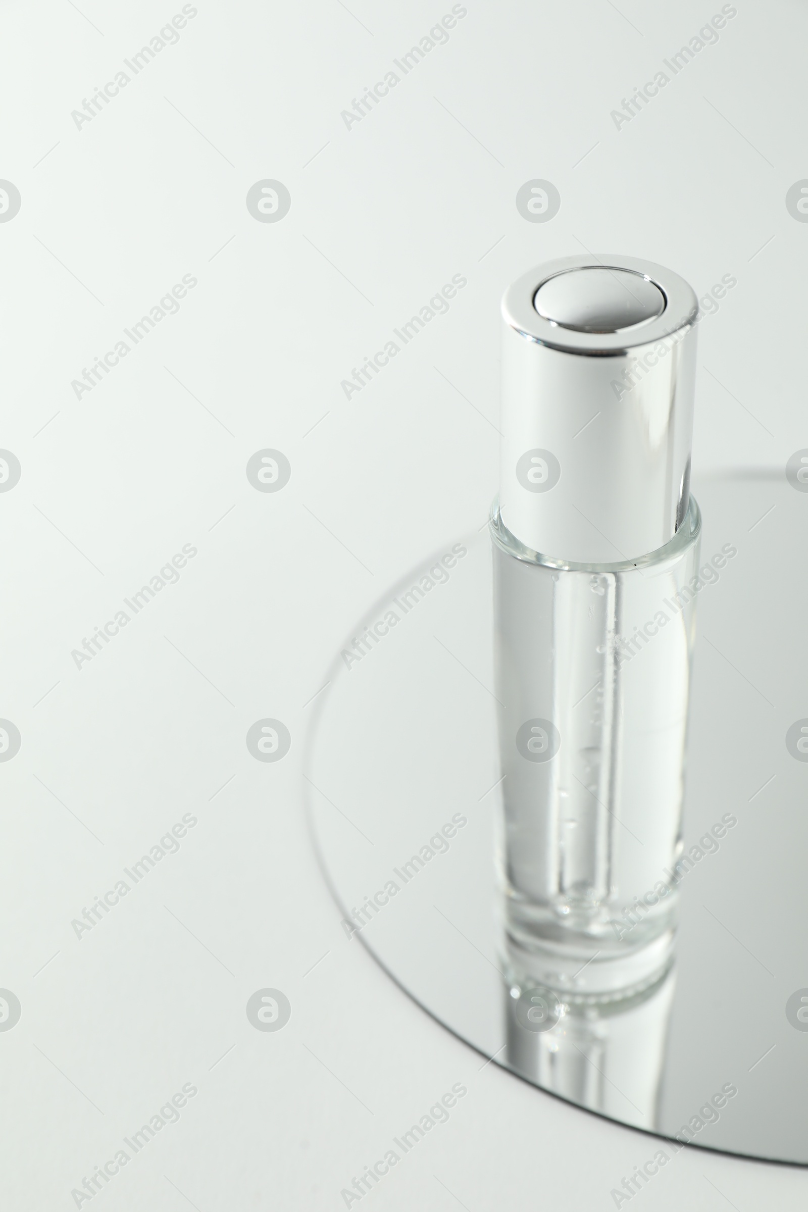 Photo of Bottle of serum and mirror on light background, closeup. Space for text