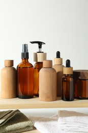 Photo of Different cosmetic products and towels on wooden shelves against white background, space for text