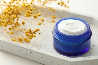 Jar of cream and yellow gypsophila flowers on table, closeup