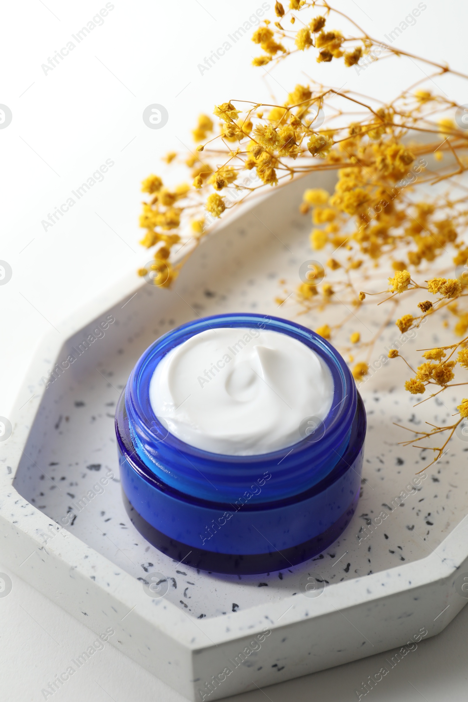 Photo of Jar of cream and yellow gypsophila flowers on white background, closeup