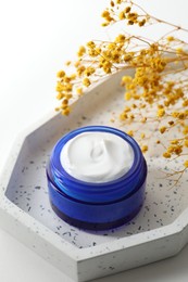 Photo of Jar of cream and yellow gypsophila flowers on white background, closeup