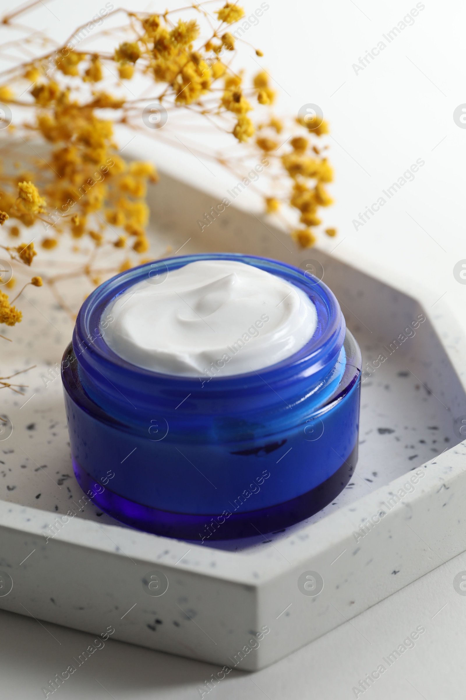 Photo of Jar of cream and yellow gypsophila flowers on white background, closeup