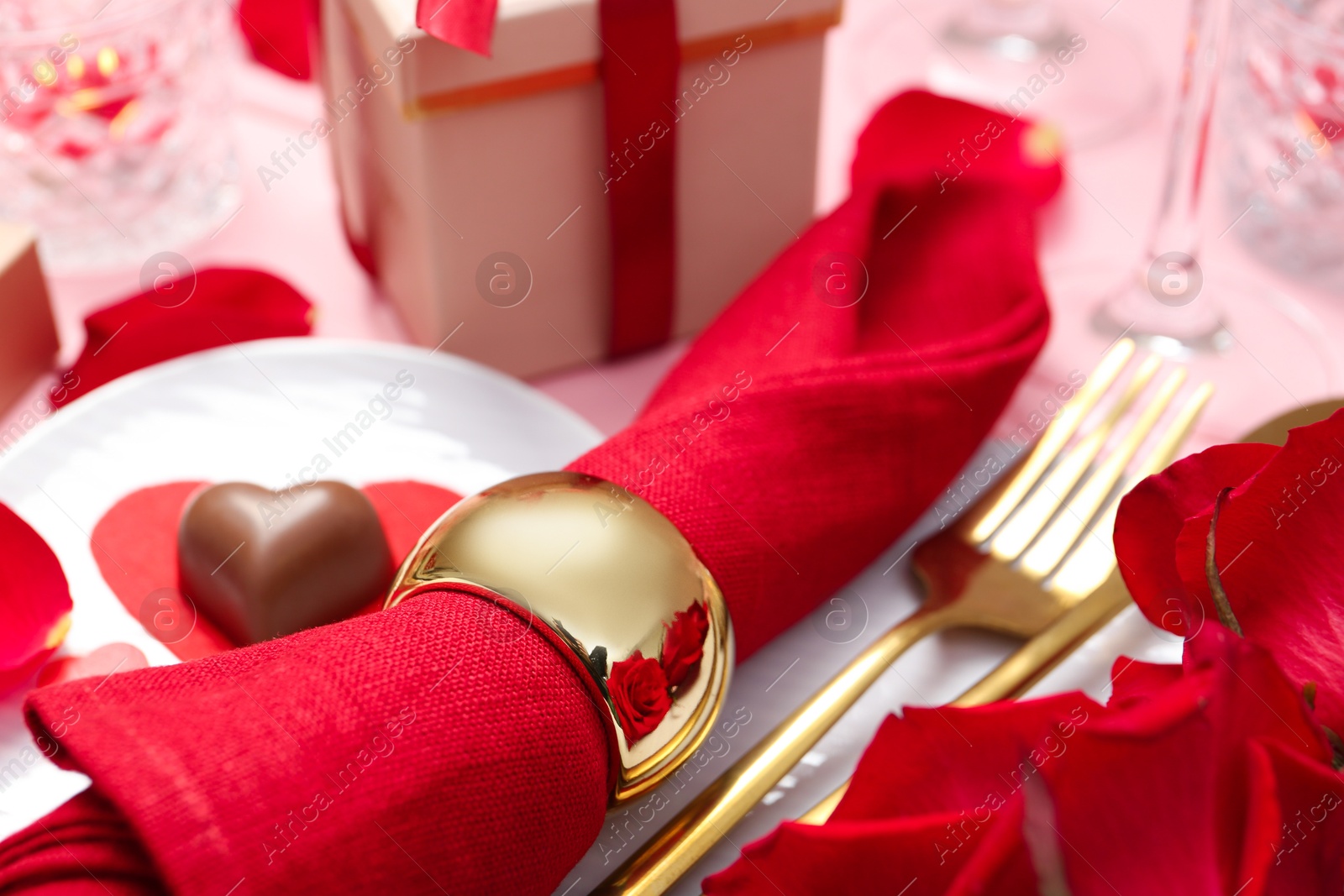 Photo of Romantic place setting for Valentine's day. Plate, cutlery and napkin on pink table, closeup