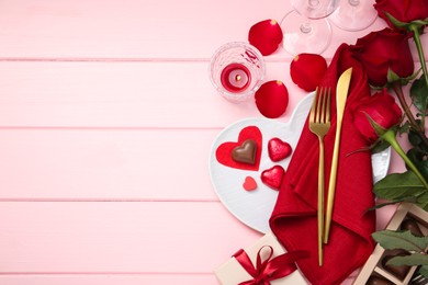 Photo of Romantic place setting for Valentine's day. Cutlery, napkin, plate, roses and decorative hearts on pink wooden table, flat lay. Space for text