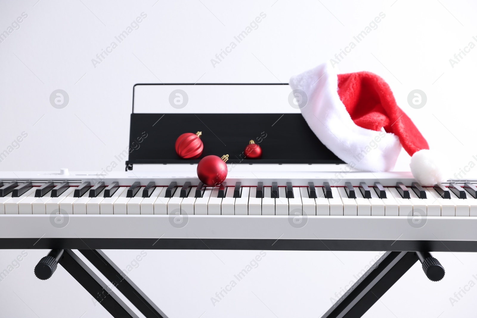 Christmas ornaments and Santa hat on synthesizer against white background, closeup Photo of Christmas ornaments and Santa hat on synthesizer against white background, closeup