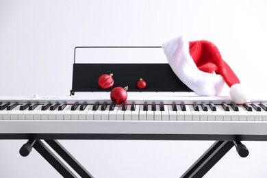 Photo of Christmas ornaments and Santa hat on synthesizer against white background, closeup