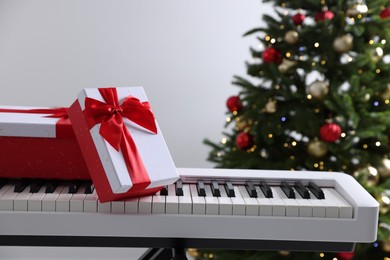 Photo of Synthesizer with gift boxes near Christmas tree indoors, closeup