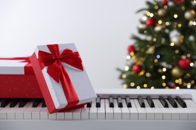 Photo of Synthesizer with gift boxes near Christmas tree indoors, closeup