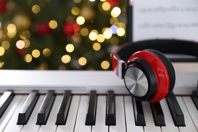 Photo of Synthesizer with headphones against blurred Christmas lights, closeup. Bokeh effect