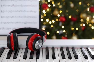 Photo of Synthesizer with headphones against blurred Christmas lights, closeup. Bokeh effect