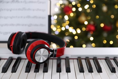 Photo of Synthesizer with headphones against blurred Christmas lights, closeup. Bokeh effect