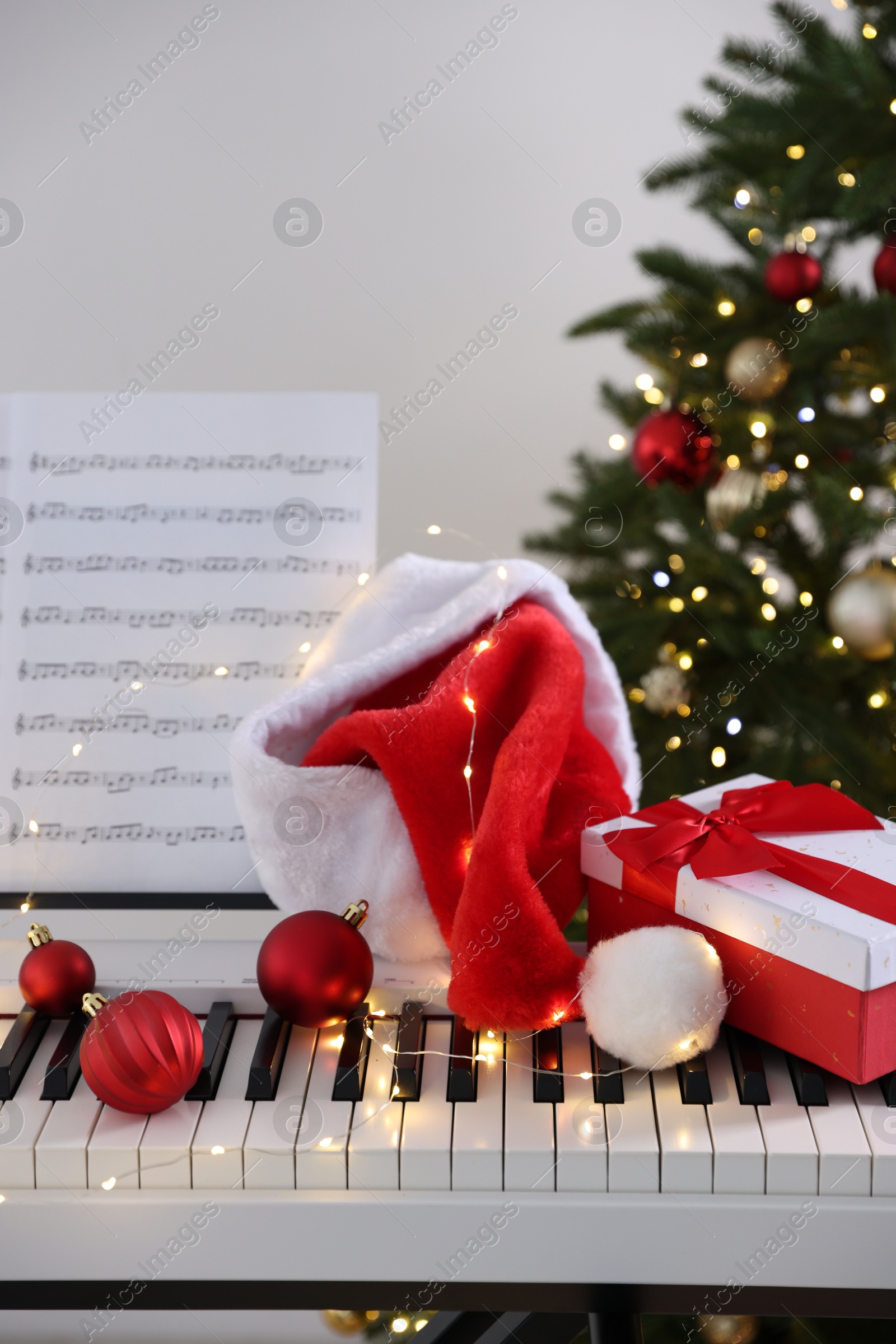 Photo of Synthesizer with music sheet and festive decor near Christmas tree indoors, closeup