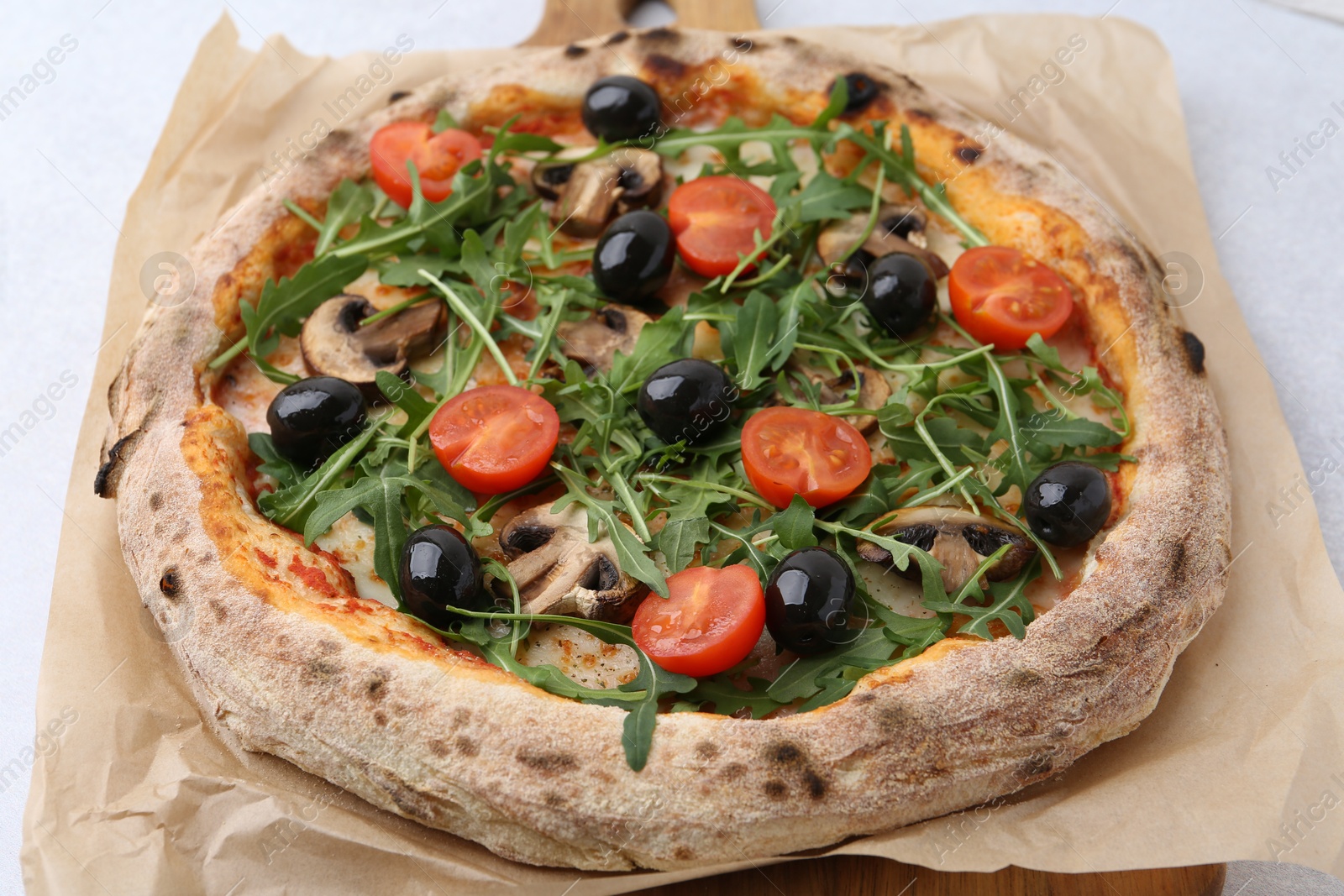 Tasty pizza with cherry tomatoes, black olives, mushrooms and arugula on white table, closeup Photo of Tasty pizza with cherry tomatoes, black olives, mushrooms and arugula on white table, closeup