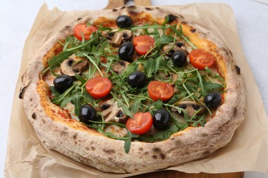 Photo of Tasty pizza with cherry tomatoes, black olives, mushrooms and arugula on white table, closeup