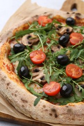 Photo of Tasty pizza with cherry tomatoes, black olives, mushrooms and arugula on white table, closeup