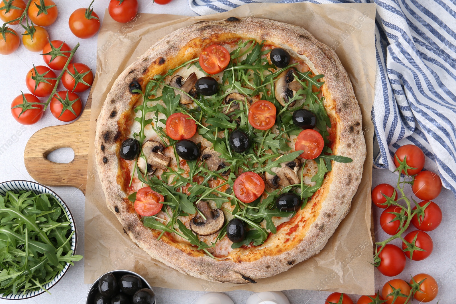Tasty pizza with cherry tomatoes, black olives, mushrooms and arugula on light grey table, flat lay Photo of Tasty pizza with cherry tomatoes, black olives, mushrooms and arugula on light grey table, flat lay