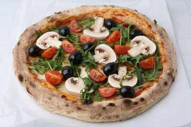 Photo of Tasty pizza with cherry tomatoes, black olives, mushrooms and arugula on white tiled table, closeup