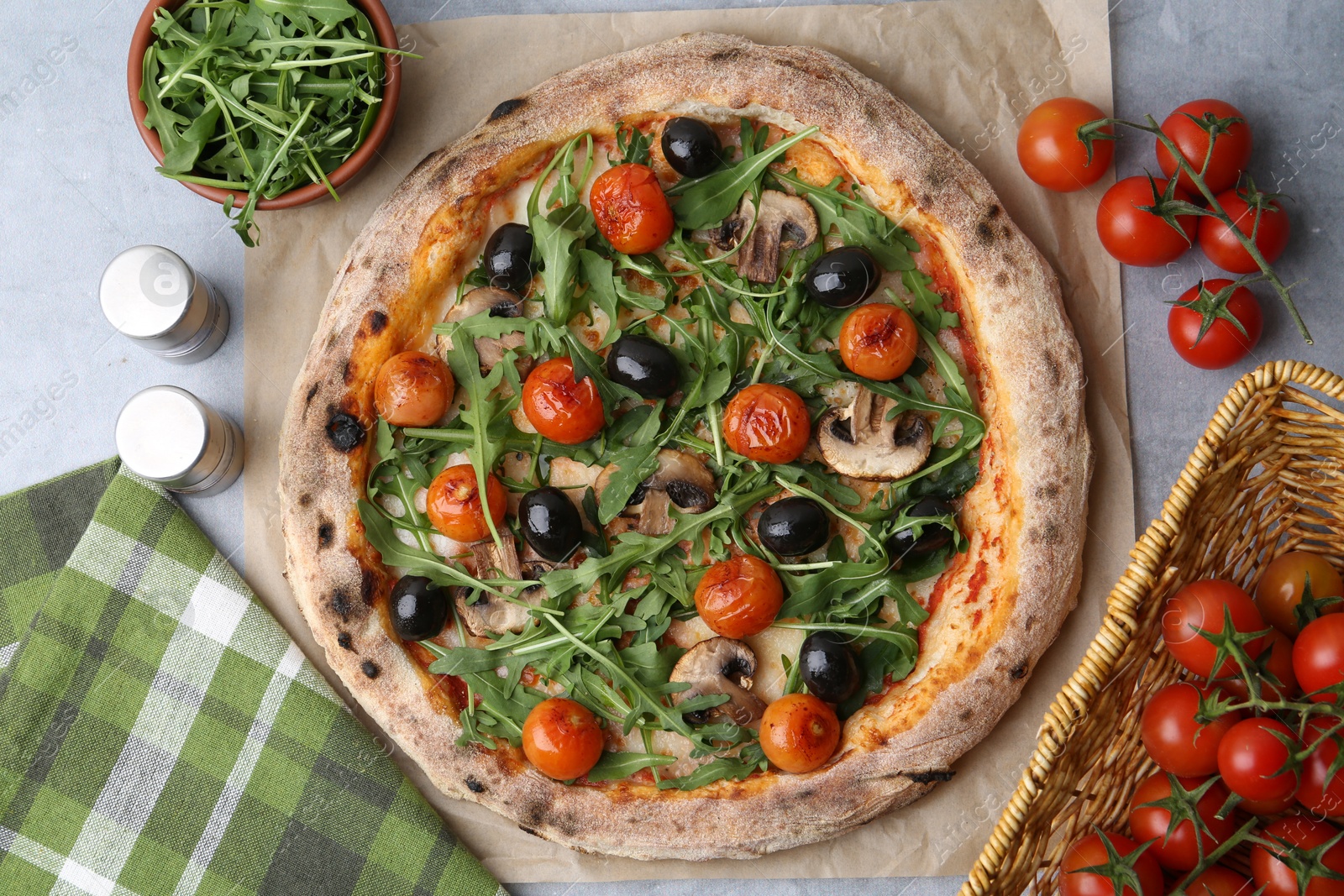 Photo of Tasty pizza with cherry tomatoes, black olives, mushrooms and arugula on grey table, flat lay