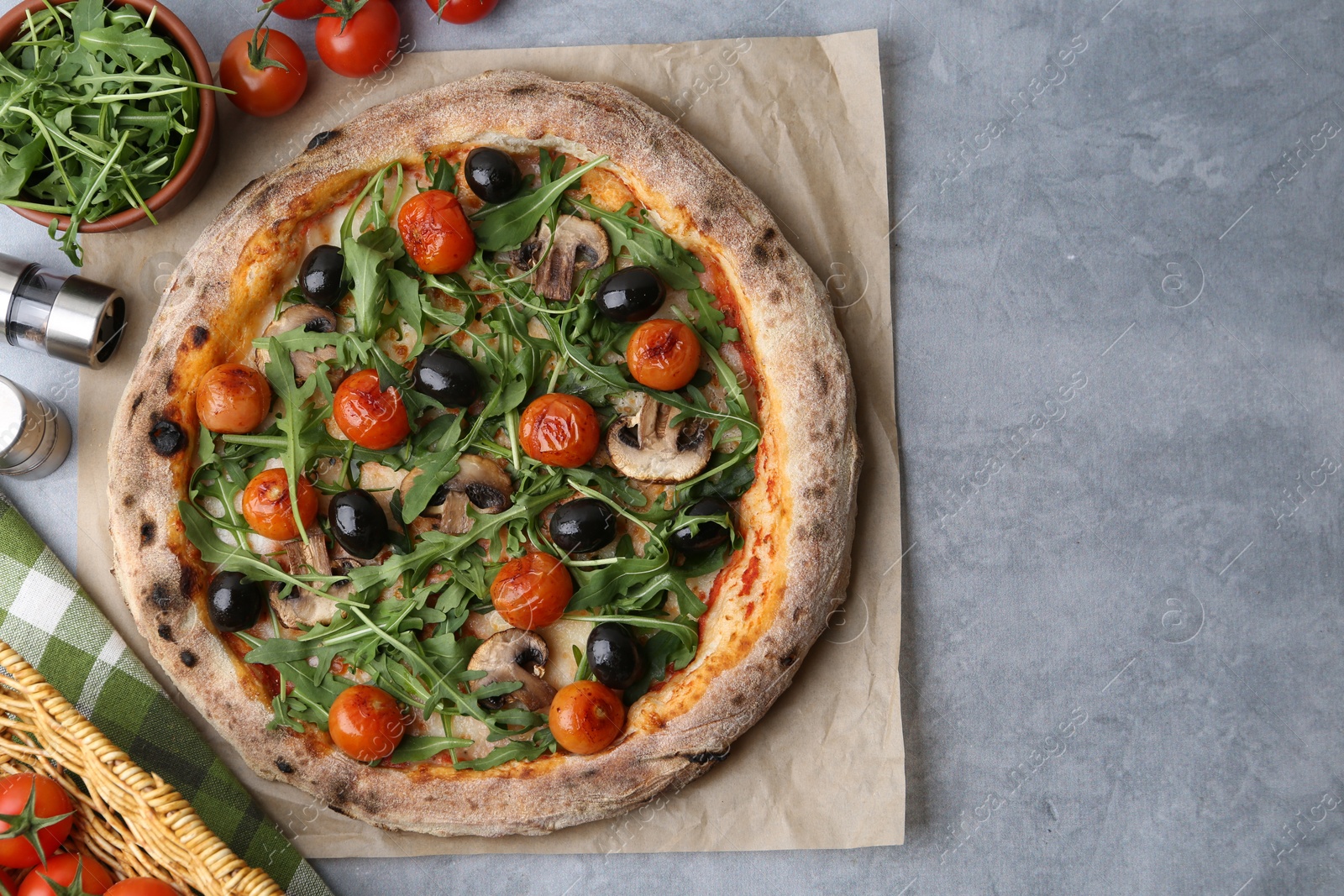 Photo of Tasty pizza with cherry tomatoes, black olives, mushrooms and arugula on grey table, flat lay. Space for text