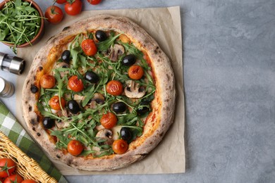 Photo of Tasty pizza with cherry tomatoes, black olives, mushrooms and arugula on grey table, flat lay. Space for text