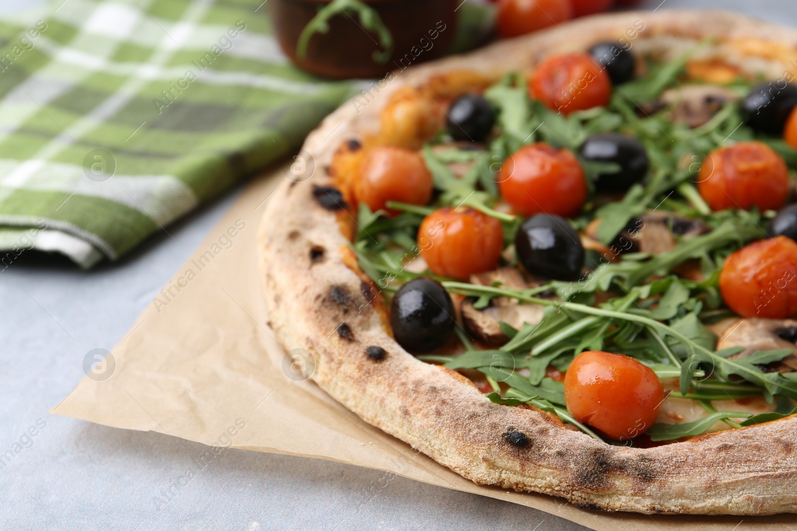 Photo of Tasty pizza with cherry tomatoes, black olives, mushrooms and arugula on grey table, closeup. Space for text