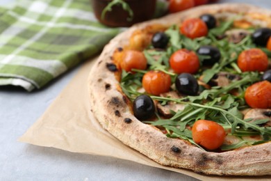 Photo of Tasty pizza with cherry tomatoes, black olives, mushrooms and arugula on grey table, closeup. Space for text