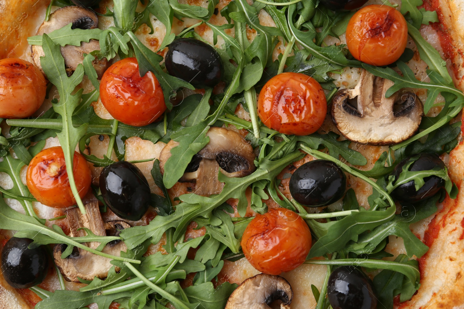 Tasty pizza with cherry tomatoes, black olives, mushrooms and arugula as background, top view Photo of Tasty pizza with cherry tomatoes, black olives, mushrooms and arugula as background, top view