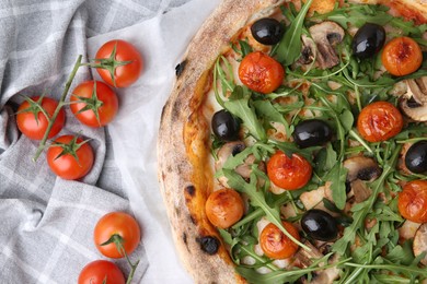 Photo of Tasty pizza with cherry tomatoes, black olives, mushrooms and arugula on table, flat lay