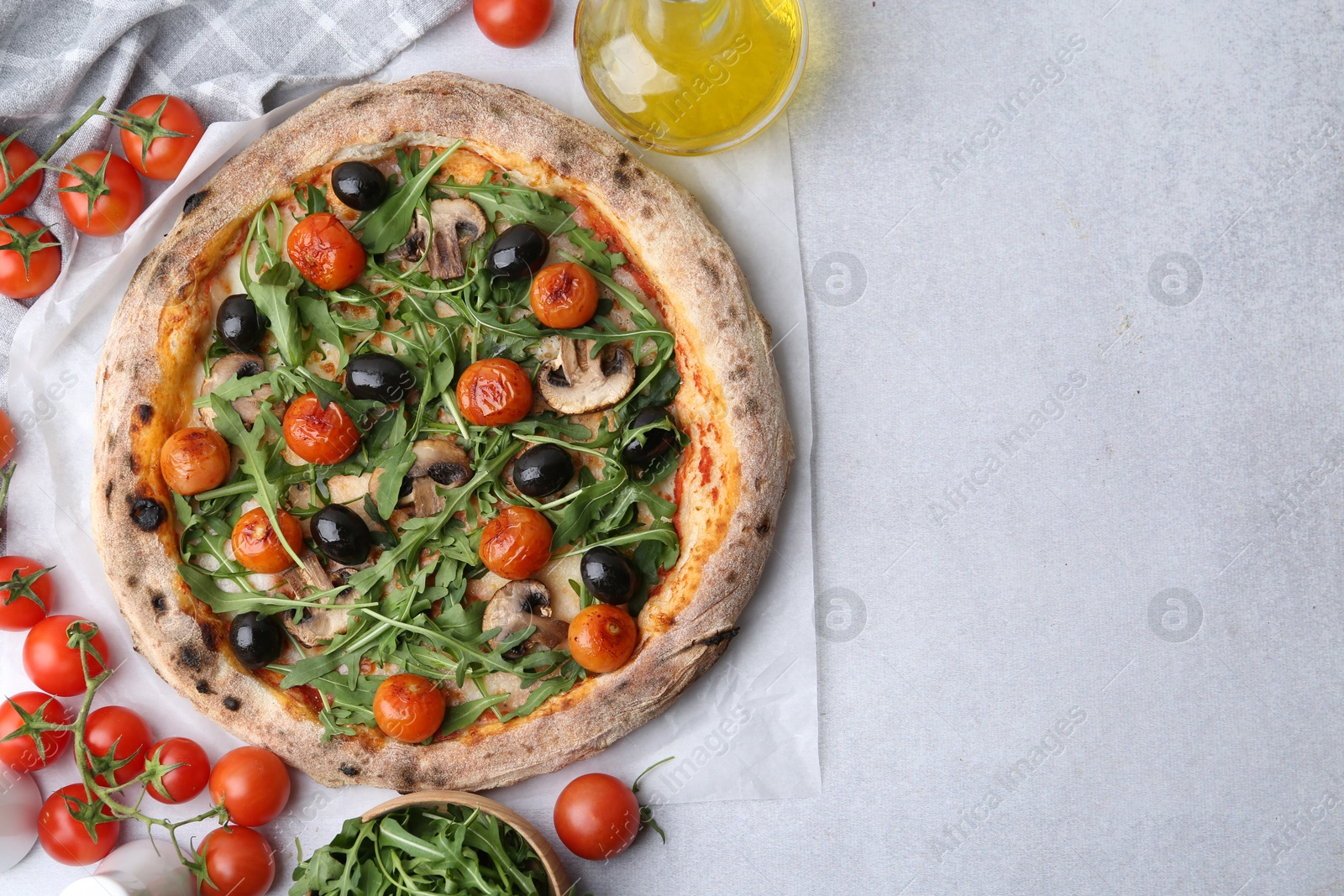 Photo of Tasty pizza with cherry tomatoes, black olives, mushrooms and arugula on light grey table, flat lay. Space for text