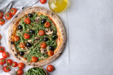 Photo of Tasty pizza with cherry tomatoes, black olives, mushrooms and arugula on light grey table, flat lay. Space for text