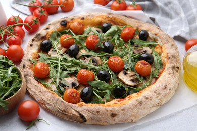 Photo of Tasty pizza with cherry tomatoes, black olives, mushrooms and arugula on white table, closeup