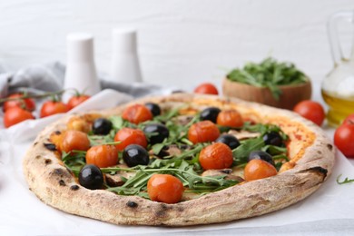 Photo of Tasty pizza with cherry tomatoes, black olives, mushrooms and arugula on white table, closeup