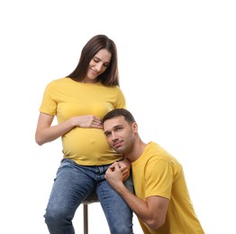 Photo of Man listening to baby in his pregnant wife's belly on white background