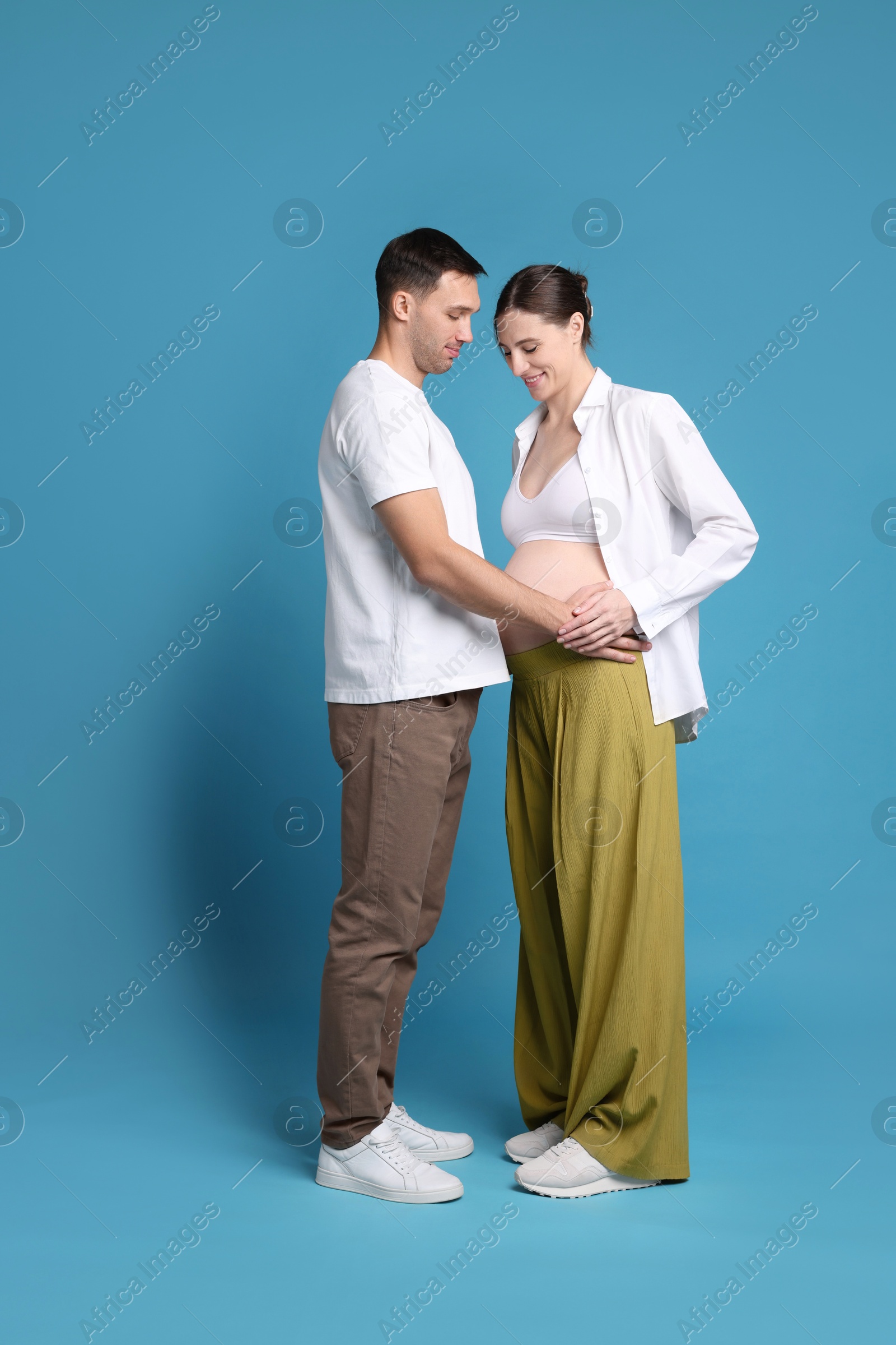 Photo of Pregnant woman and her husband on blue background