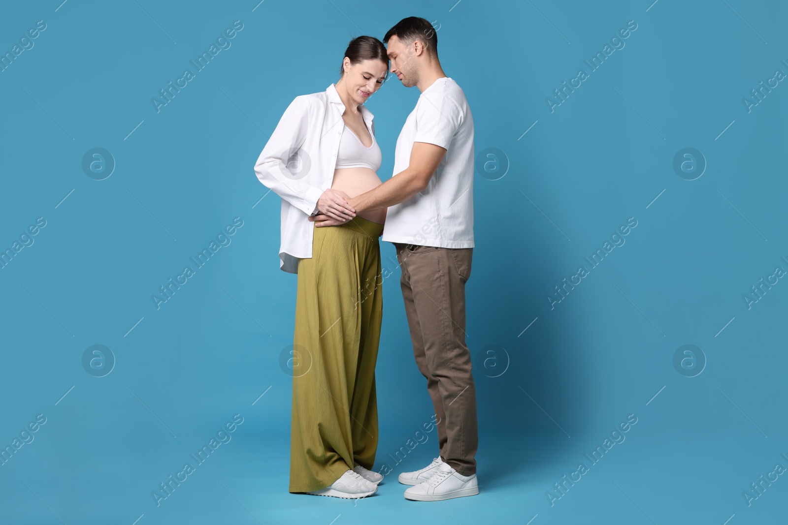 Photo of Pregnant woman and her husband on blue background