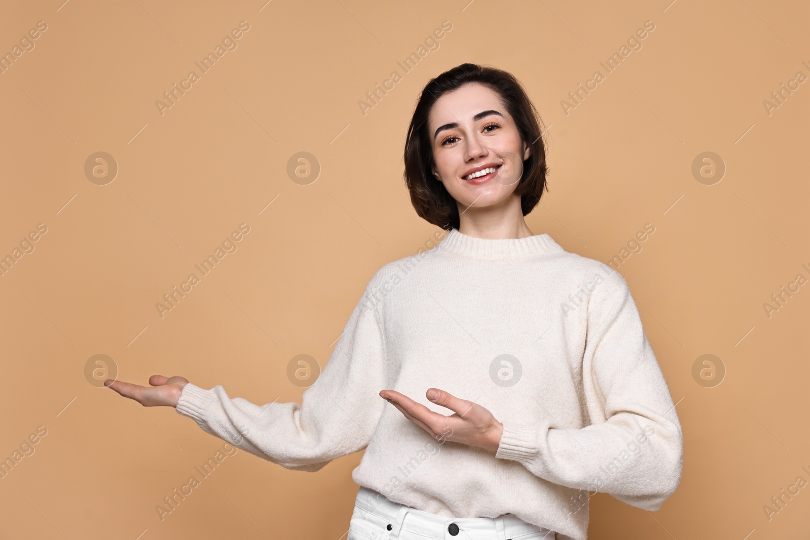 Photo of Cheerful woman welcoming friends or guests on brown background